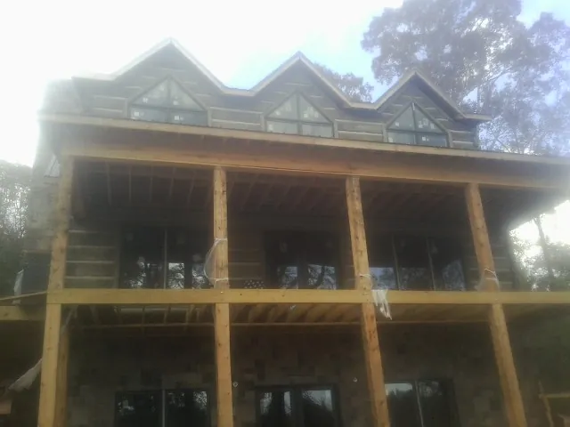 Dormers and porch framing on a large log home under construction — Roof Coating work by our crew in Eastport